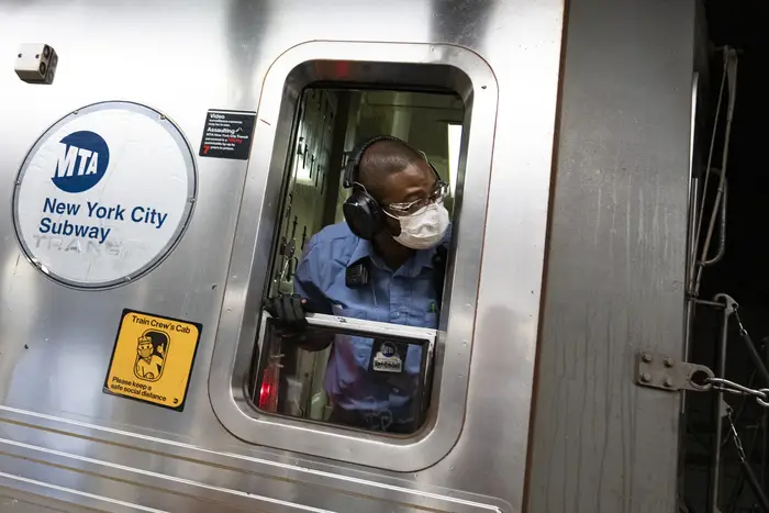 A subway conductor peer out a train window while on the job.